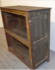 Brown wooden Tibetan bookshelf with two shelves, hand-painted faded floral designs on front edges, front view.