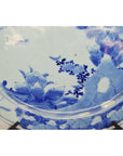 Close-up of blue and white porcelain plate with floral designs on a decorative stand.