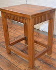 Brown Art Deco stool with wooden legs on a wood floor, positioned near a white brick wall in Shanghai.