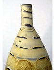Close-up of a large earth-toned ceramic vase with a tall neck and wavy beige and black sand dune-like lines.