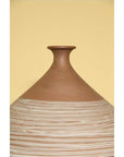 Close-up of a brown hand-made ceramic vase with a narrow neck and white stripes, on a light yellow background.