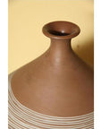 Close-up of a white-striped ceramic vase with a narrow neck, set against a yellow background.