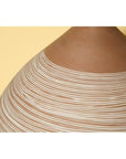 Close-up of large white-striped ceramic vase against a pale yellow background.