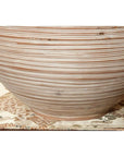 Brown and white ceramic vase with thin stripes on patterned cloth.