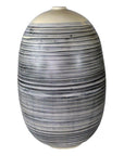 White ceramic vase with thin black stripes, rounded shape, close-up view.