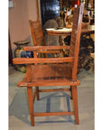 Brown wooden Arts & Crafts style chair with slatted back and seat, side view indoors next to a round table.