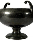Close-up of a metallic hammered Asian bowl with two handles, wide opening, and short base; in good condition.