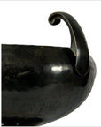 Close-up of black ceramic hammered Asian bowl with single curved handle on white background.