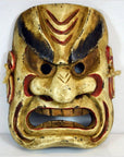 Close-up of a gold and red Balinese dancing mask with exaggerated angry details, traditional style.