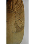 Close-up of a light brown carved Balinese mask with intricate patterns, close-up view.