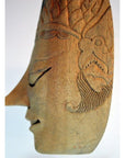 Brown wood Balinese masks with carved features and intricate patterns, side profile view on a plain background.