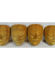 Close-up of four intricately patterned Balinese masks with serene, closed eyes on a white background.