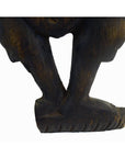 Close-up of a brown hand carved wood Balinese temple dancer sculpture, showing both legs and feet on white background.