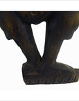 Close-up of a brown hand carved wood Balinese temple dancer sculpture, showing both legs and feet on white background.