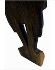 Close-up of a brown wood Balinese hand carved temple dancer silhouette, angled on white background.