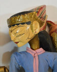 Close-up of a Balinese puppet figure in blue clothing, gold headdress, and painted face detailing.