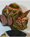 Close-up of a hand-carved wood Balinese puppet head with intricate gold, red, and black traditional carvings.