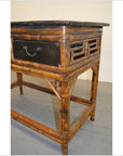 Close-up of black lacquered bamboo desk with bamboo-style legs and black tabletop on gray floor.