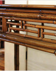 Close-up of bamboo and natural lacquer console table with detailed fretwork on side panel.