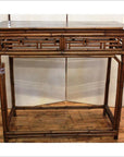 Natural bamboo and lacquer console table with fretwork front on hardwood floor.