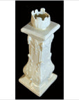 White porcelain candle holder with floral designs, set against a dramatic black background, close-up view.