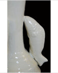 White porcelain candle holder with sculptural dolphin handles, close-up against a black background.