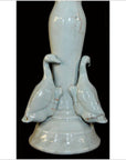 White porcelain candle holder with two white ducks at the base, Blanc de Chine style, on a black background.