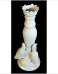 White porcelain candle holder with scalloped top and two duck figures, close-up on black background.