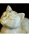 White porcelain cat figurine with crackle finish and gold stickers, close-up on black background.