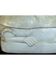 Close-up of white porcelain cat figurine, showing sculpted paw and tail on a rectangular base.