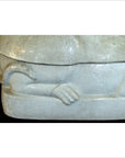 Close-up of white porcelain cat figurine, showing sculpted paw and tail on a rectangular base.