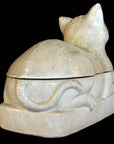 Cream-colored porcelain cat with crackled glaze, viewed from back and side against black background.
