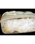 White porcelain cat on a weathered, discolored rectangular base with patina underneath.