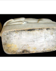 White porcelain cat on a weathered, discolored rectangular base with patina underneath.
