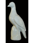 White porcelain dove statue, Blanc de Chine, against a solid black background.