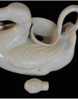 White porcelain duck-shaped gravy boat with handle and matching front stopper, close-up view.
