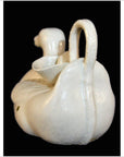 White porcelain duck teapot with curved handle, close-up on black background.