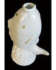 White porcelain fish-shaped vase with wave base, close-up, set against a black background.