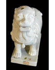 White Blanc de Chine porcelain Foo-Dog with detailed mane on a rectangular base against a black background.