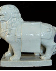 White porcelain Foo Dog figurine with detailed mane and blanket on base, set against a black background.