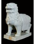 White porcelain Foo Dog with detailed mane on a rectangular base, close-up against a black background.
