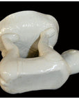 White porcelain monkey lying on back balancing large bowl with raised legs and arms, studio background.