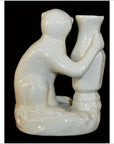 White porcelain monkey figurine hugging tall vase, close-up against dramatic black background.