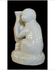 White porcelain monkey figurine holding vase on rounded base, modern style, close-up on black background.