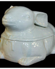 White porcelain rabbit figurine with scarf, lying down on a black background, Blanc de Chine style.