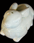 White porcelain rabbit-shaped dish with lid, Blanc de Chine style, close-up on black background, price stickers visible.