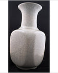 White porcelain Blanc de Chine vase with narrow neck and rounded body, close-up against a black background.