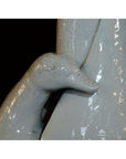 Close-up of glossy light gray porcelain swan head and neck from Blanc de Chine vase against black background.
