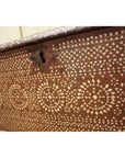 Close-up of a brown wood blanket chest with geometric bone inlay patterns and a metal keyhole.