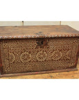 Brown wooden blanket chest with white geometric bone inlay patterns on the front, set on a wooden floor.